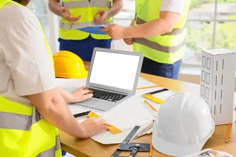 Engineers collaborating on construction project with laptop and blueprints Stock Photos