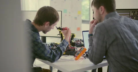 Engineers Collaborating on Robotic Arm Programming and AI Development. Stock Footage 306739919