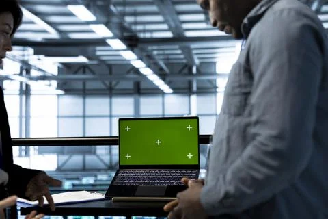 Engineers in data center using automation tools on green screen mockup laptop Stock Photos