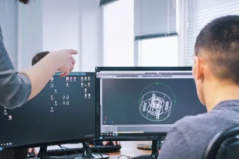Engineers discuss creation of a 3D drawing of the equipment parts. Stock Photos