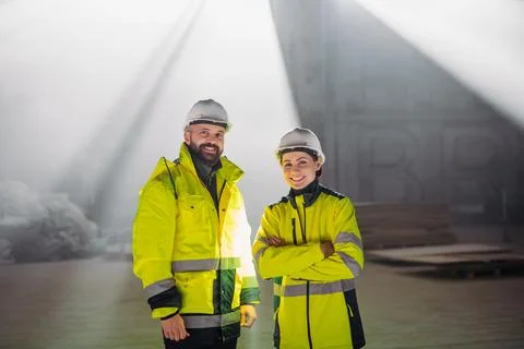 Engineers discussing construction plans using a tablet on site. Stock Photos