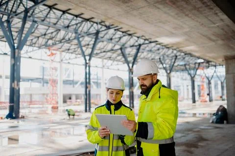 Engineers discussing construction plans using a tablet on site. Stock Photos