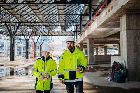 Engineers discussing construction plans using a tablet on site. Stock Photos