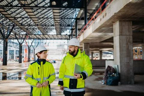 Engineers discussing construction plans using a tablet on site. Stock Photos