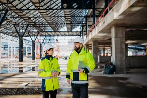 Engineers discussing construction plans using a tablet on site. Stock Photos