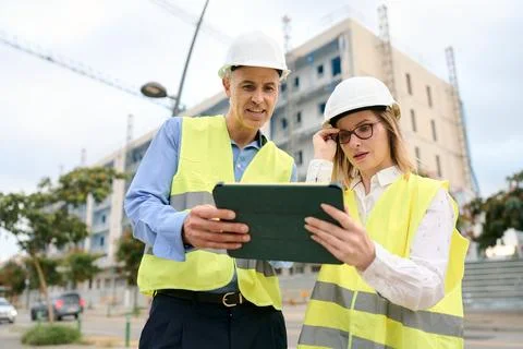 Engineers discussing construction project plans using digital tablet Stock Photos