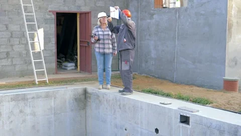 Engineers discussing plans for empty swimming pool construction Video stock 315408395