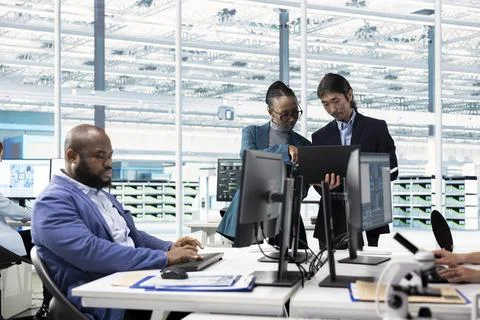 Engineers examining microchip circuit design on computer monitors Stock Photos