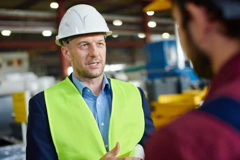 Engineers in hard hats talking to each other at the industrial plant. Stock Photos