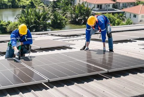 Engineers in helmets installing solar panel Stock Photos