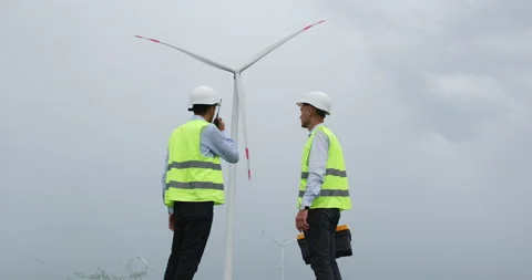 Engineers in helmets look at wind turbine and shake hands Stockbeeldmateriaal 160222112