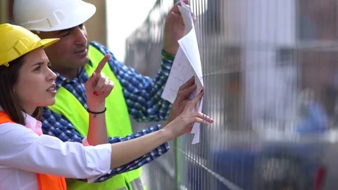 Engineers holding plans and inspecting the construction site among scaffolding Stock Footage 74410009