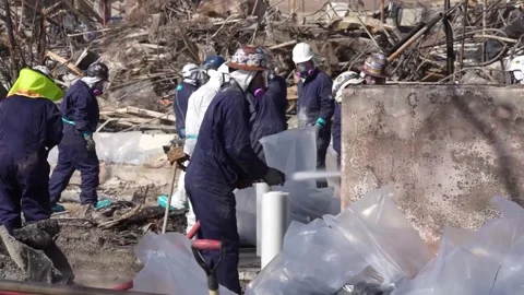 Engineers hosing and clearing debris from school destroyed by wildfire Stock Footage 300966255