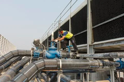 Engineers inspect machine operations. Cooling towers in large buildings For s Stock Photos
