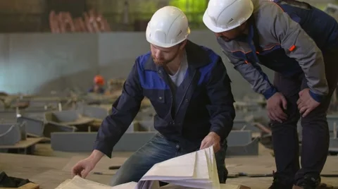 Engineers look at building plans and discuss stages of construction in heavy Stock Footage 65249986