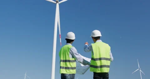 Engineers look at project drawing against rotating windmills Stockbeeldmateriaal 164212074