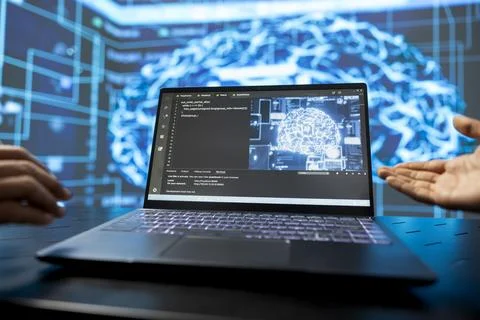 Engineers looking at laptop displaying source code and AI model Stock Photos