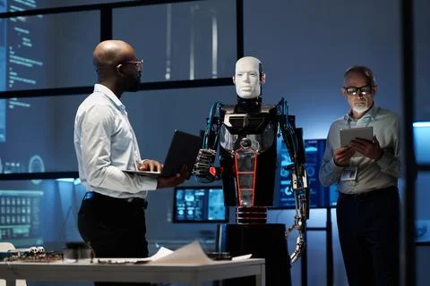 Engineers programming robot with gadgets Photos