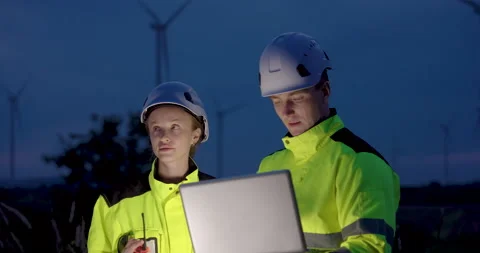 Engineers reviewing laptop screen during night wind farm inspection, Stock Footage 324790750
