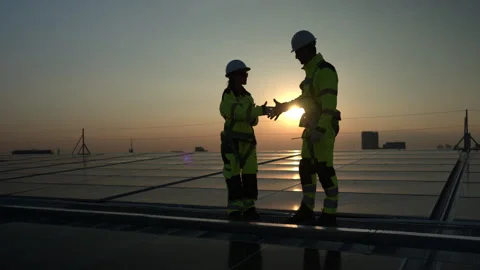 Engineers reviewing solar system data on a rooftop at sunset 스톡 동영상 339648413