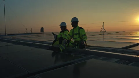 Engineers reviewing solar system data on a rooftop at sunset 스톡 동영상 339649860