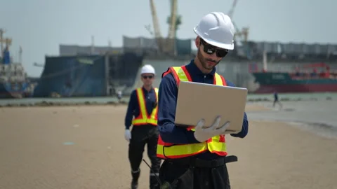 Engineers in safety gear walk beside the water at a port inspected Stock Footage 340076452