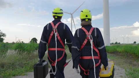 Engineers in safety gear working at height walking to the wind turbine Stock Footage 220021010