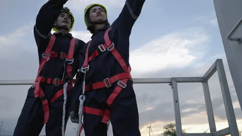 Engineers in safety gear working at height stood talking after doing repair Stock Footage 220637398