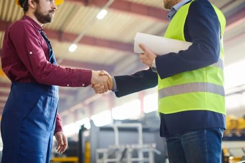 Engineers shaking hands in a close up shot at the industrial plant. Stock Photos