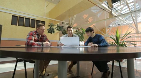 Engineers sit at round wooden table and discuss project Stock-Footage 64957585