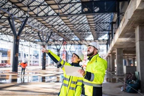 Engineers standing outdoors on construction site, holding tablet. Stock Photos