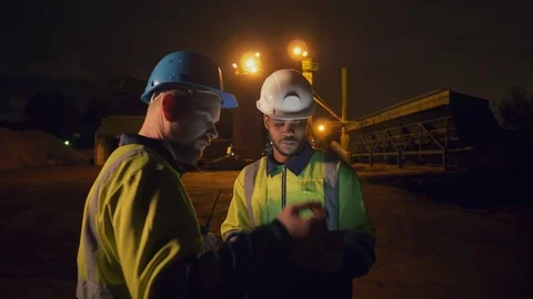 Engineers standing outdoors on road construction site, holding tablet and walkie Stockbeeldmateriaal 124303869