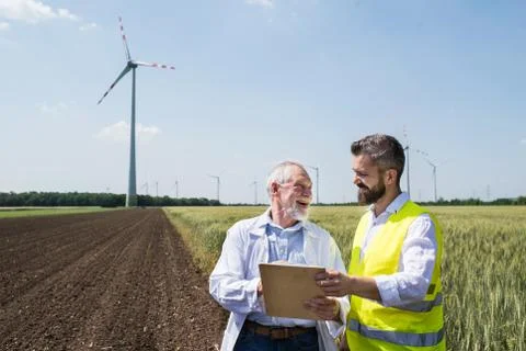 Engineers standing on wind farm, making notes. Stock Photos