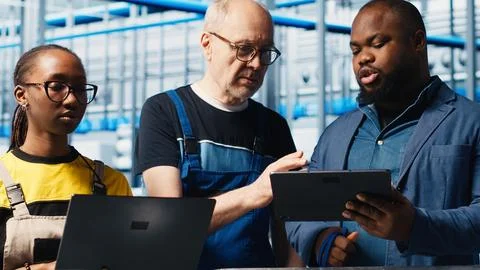 Engineers talk with manager overseeing smart factory, showing collected metrics Foto stock