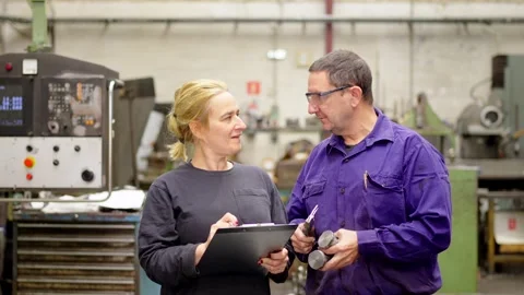 Engineers talking while doing paperwork in a cnc factory Stock Footage 258397672