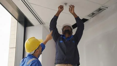Engineers team installing fire sprinkler in office at building site Fotos de archivo