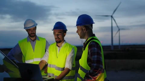 Engineers teamwork discussing renewable energy project at wind turbine farm Stock Footage 285986482
