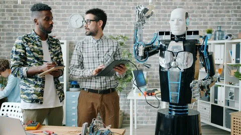 Engineers testing robot in office working with tablet discussing ai smiling Vídeos de archivo 119573298