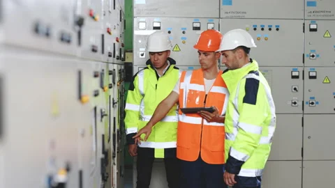 Engineers in uniform and helmets with digital tablet do pre-commissioning works Stock Footage 194617562