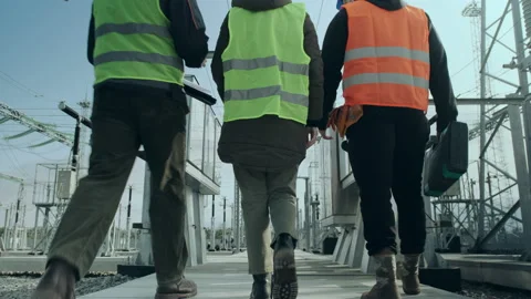Engineers walk along asphalt path against power station Video stock 142971152