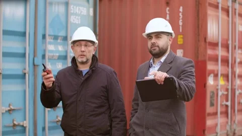 Engineers walking and discussing in front of a stacked cargo container. A Stock Footage 306217525