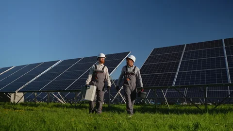 Engineers walking and pointing at solar panels in solar farm Video stock 314406465