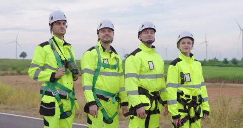 Engineers wearing helmets slowly standing together near wind turbines, confident Stock Footage 337165814