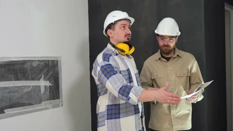 Engineers in white helmets are discussing repair at a construction site indoors Stock Footage 235169130