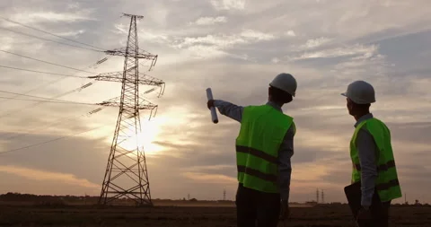 Engineers work against the background of a high-voltage pole. Stockbeeldmateriaal 141147869