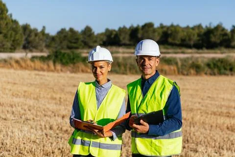 Engineers in work clothes stand on a sunny day in a rural field. Stock Photos