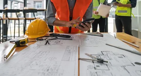 Engineers working on blueprints and construction plans. Building engineers Fotos de archivo