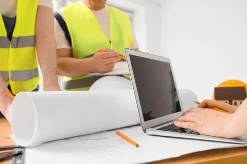 Engineers working on building plans with laptop and blueprints Stock Photos
