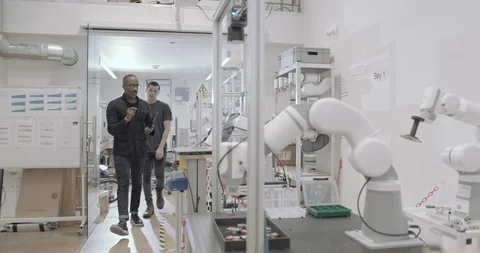 Engineers working on a programming for robotic arm Stock Footage 121730012