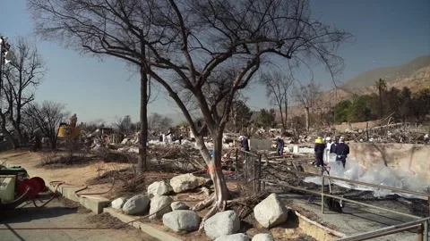 Engineers working to remove debris from a school destroyed by wildfire Stock Footage 300966354